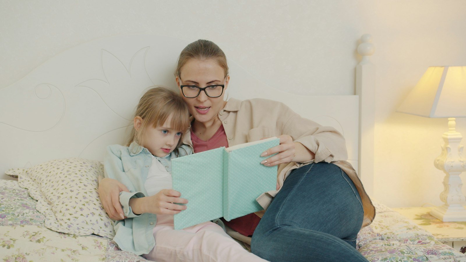 Mother and daughter reading a book together in bed